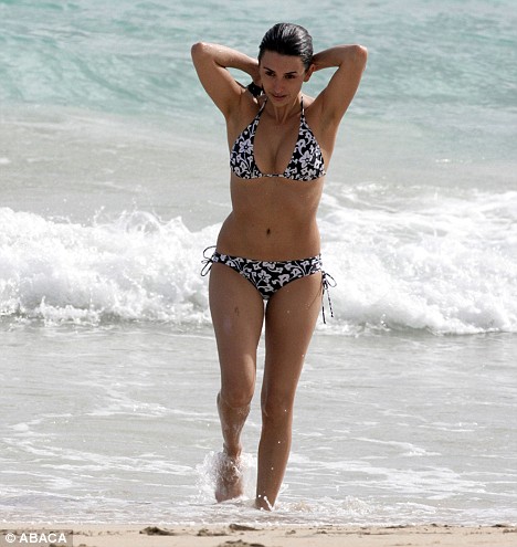 Mit ihre schlanke Körper und Dunkelbraun Haartyp ohne BH (BH-Größe 34C) auf Strand im Bikini
