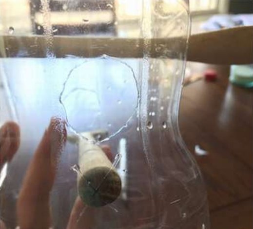 Оклеиваем края окон изолентой  /></p>
<p>Теперь займёмся крышкой. В центре сделаем крестообразный прорез, проденем туда концы веревки и завяжем их узлом. Прикрутим крышку к бутылке и кормушка готова.</p>
<p>Корм в такую кормушку добавлять довольно удобно. Отворачиваем корпус (крышка остаётся висеть на ветке), насыпаем корм и прикручиваем кормушку обратно.</p>
<div title=