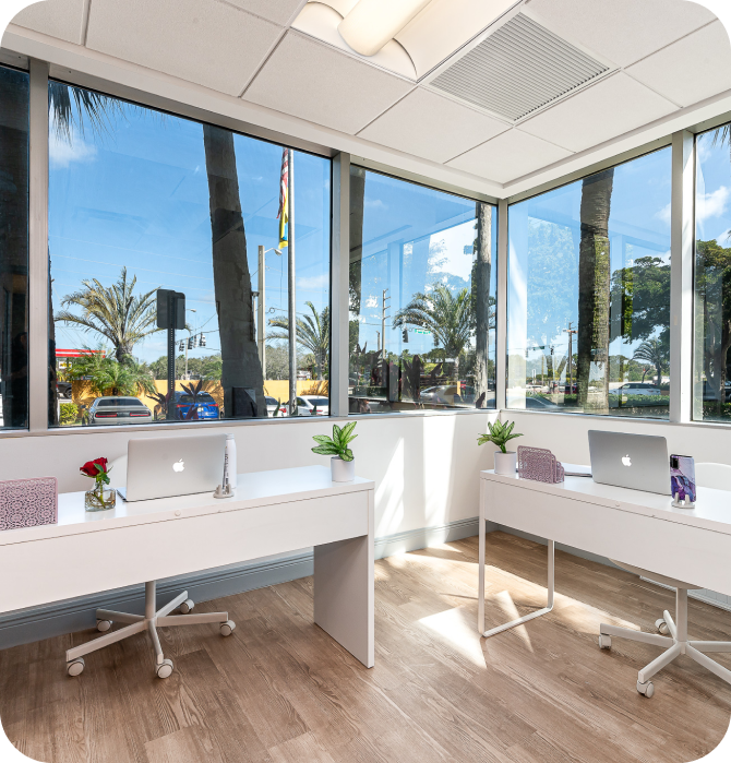 Minimalistic office setup with a single desk, laptop, and modern art on the wall. The room is well-lit with natural light from a window, creating a calm and focused workspace.