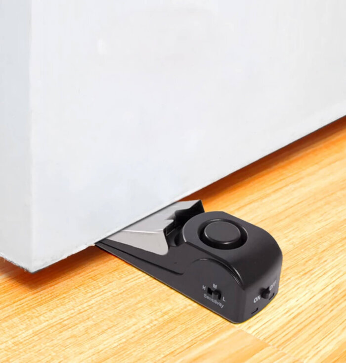 Alarma tope de puerta de color negro.