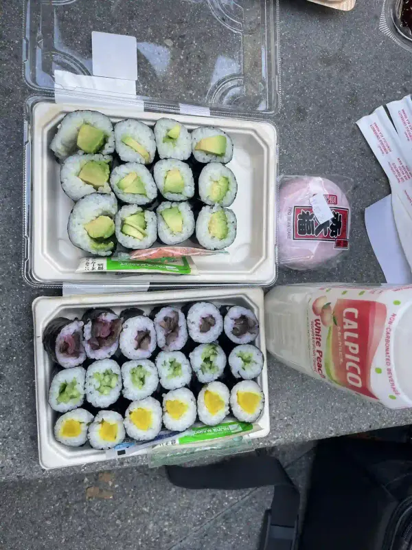two open sushi boxes, a red bean cake, and a white peach calpico.