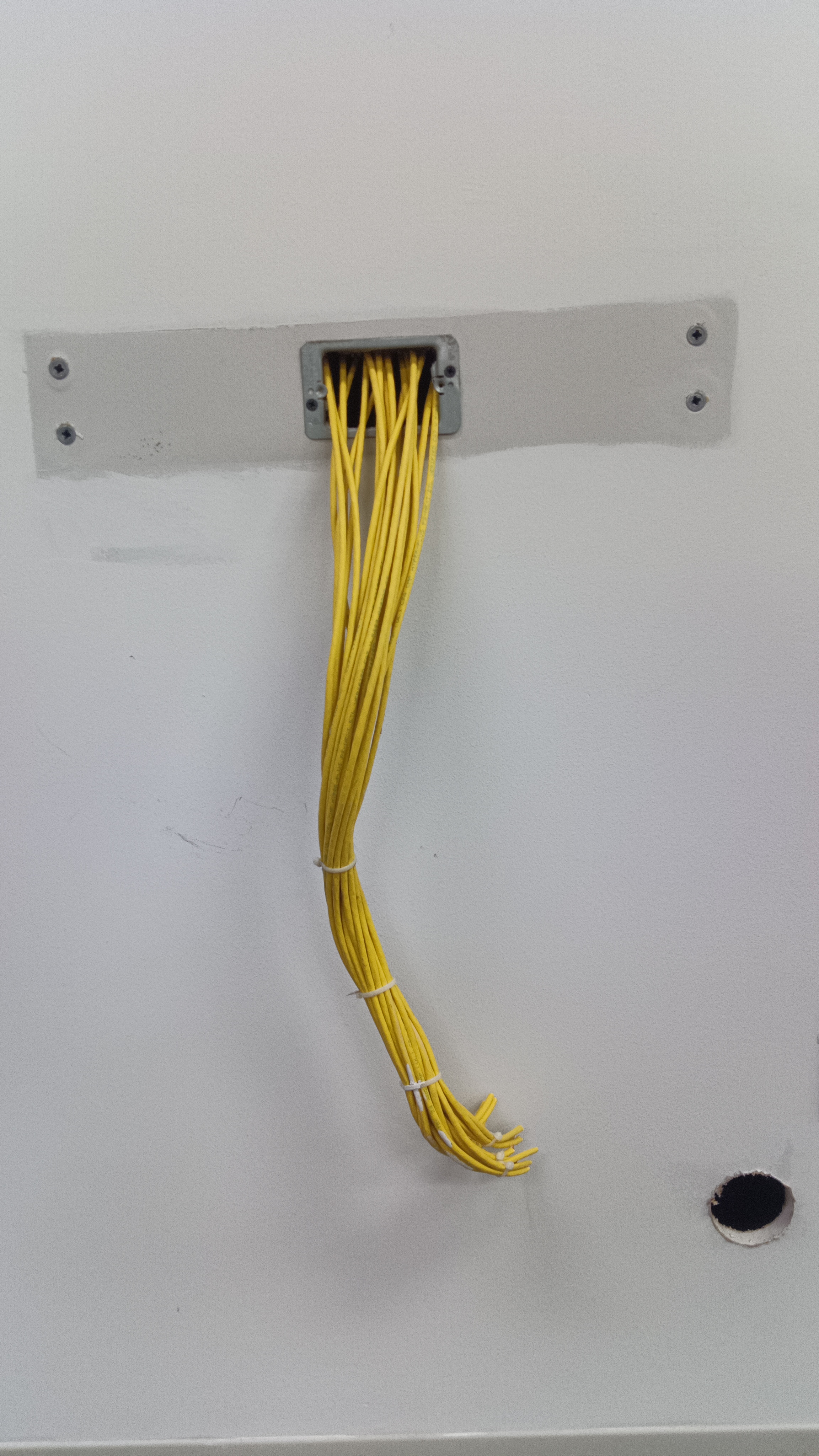 A bundle of yellow cables spilling from a wall outlet