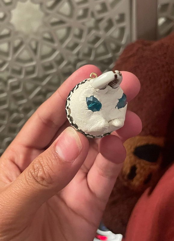 a photo of a little beetle-looking creature made out of a bottle cap, some clay for the head, a sea shell for the pinsers, and little blue gems for the eyes