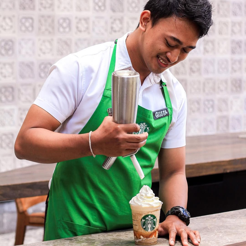 Barista Starbucks Kopi sedang menyajikan minuman untuk pelanggan