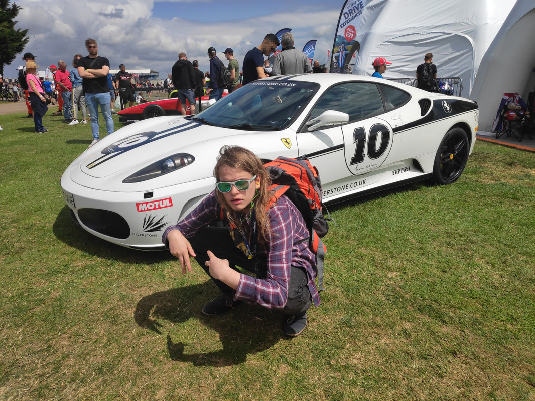 Chris posing in front of a white sports car