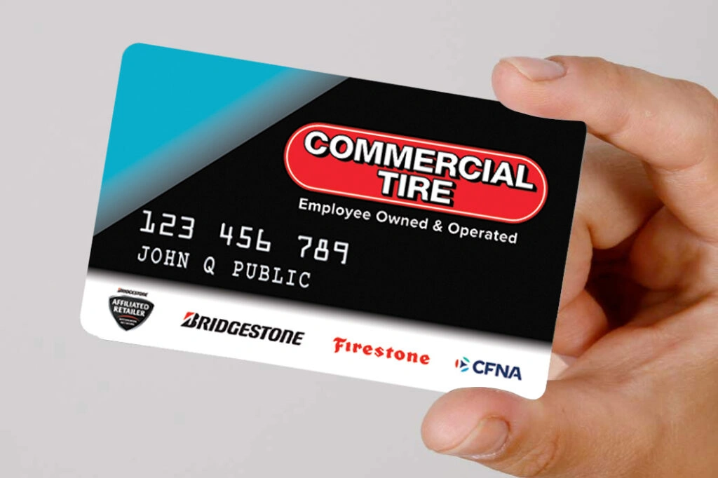 Hand holding a Commercial Tire financing card displaying logos of Bridgestone, Firestone, and CFNA.