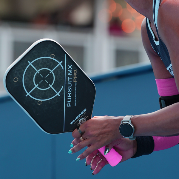A lifestyle shot of a player holding an Engage Pursuit Pro MX paddle on a pickleball court.