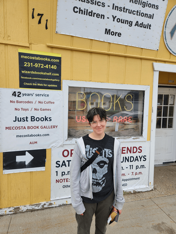Mel standing in front of a used bookstore storefont