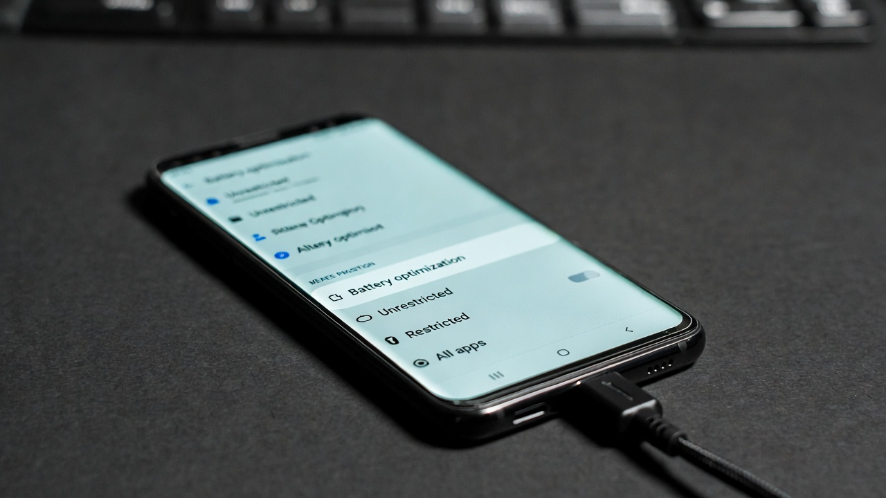 Smartphone showing battery optimization settings menu with charging cable connected