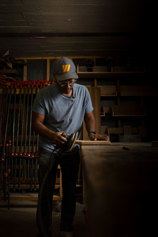 Commercial photography of skilled trades professional sanding wood in workshop