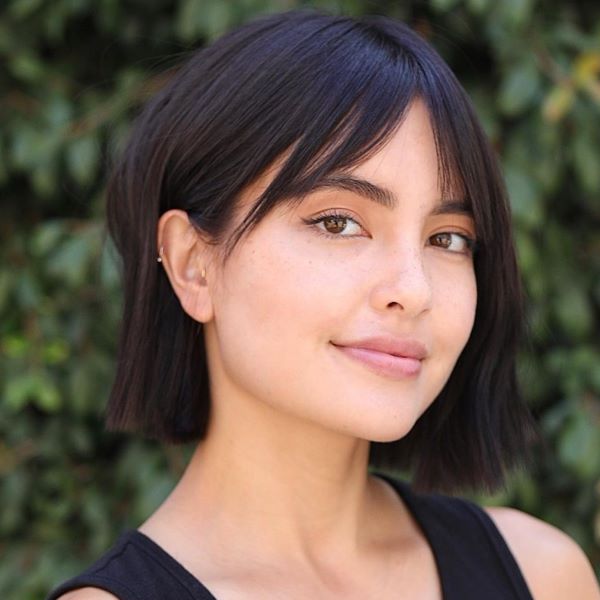 devojka sa modernom, simpatičnom bob frizurom sa razdeljenim šiškama