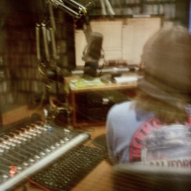 From behind, DJ sitting at studio desk