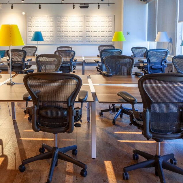 Multiple rows of coworking chairs and desks in large area