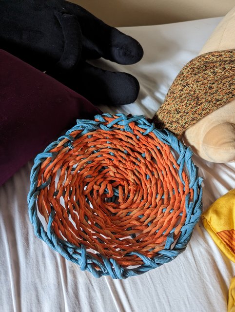 hand woven basket with an orange base and blue rim.