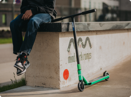 Image shows a man seating near to trick scooter