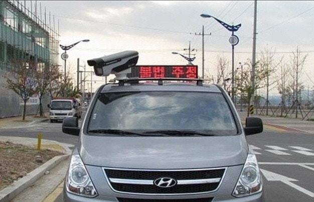 Mobile illegal parking enforcement car displaying a red electronic sign reading illegal parking enforcement in Korea