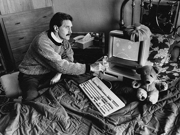 John McAfee posing with his computer in his early days