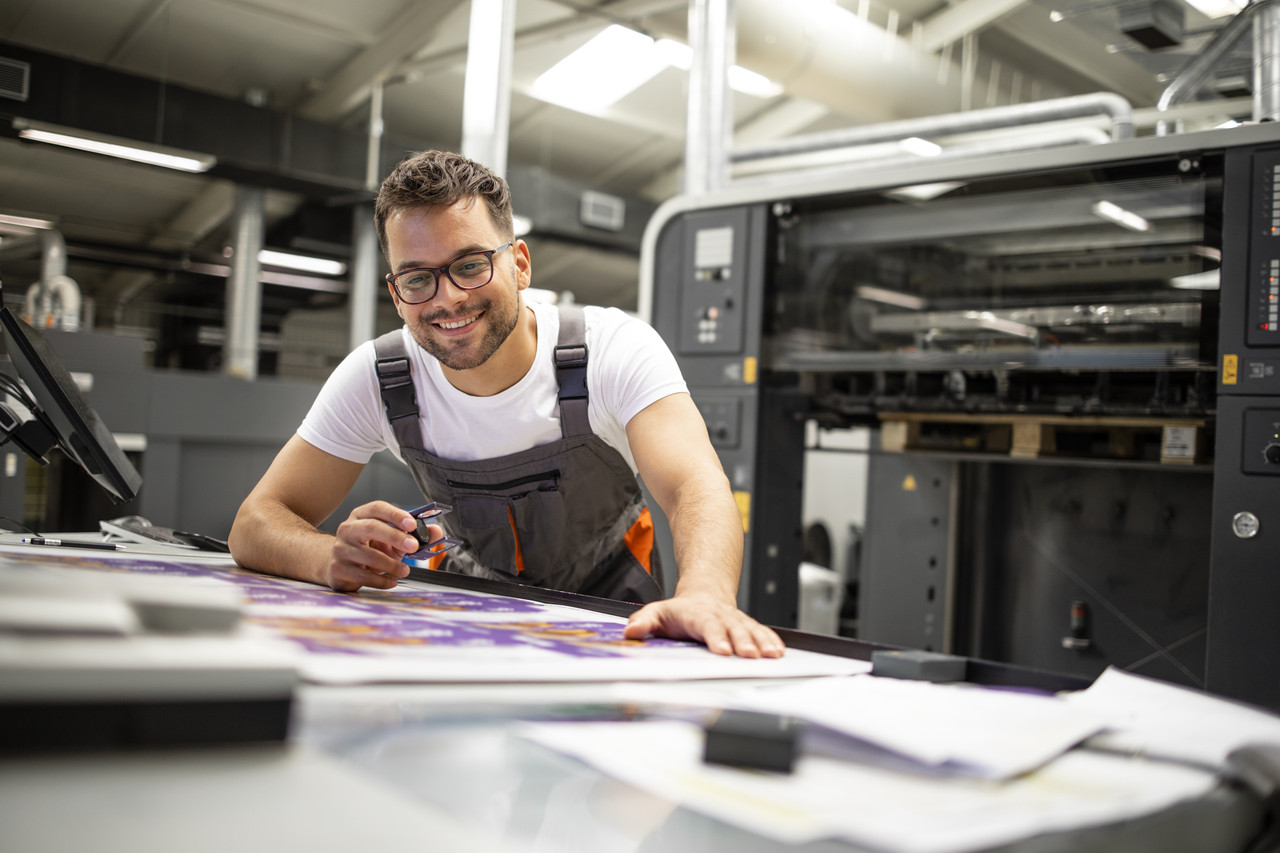 print house worker controlling printing process quality checking colors with magnifying glass