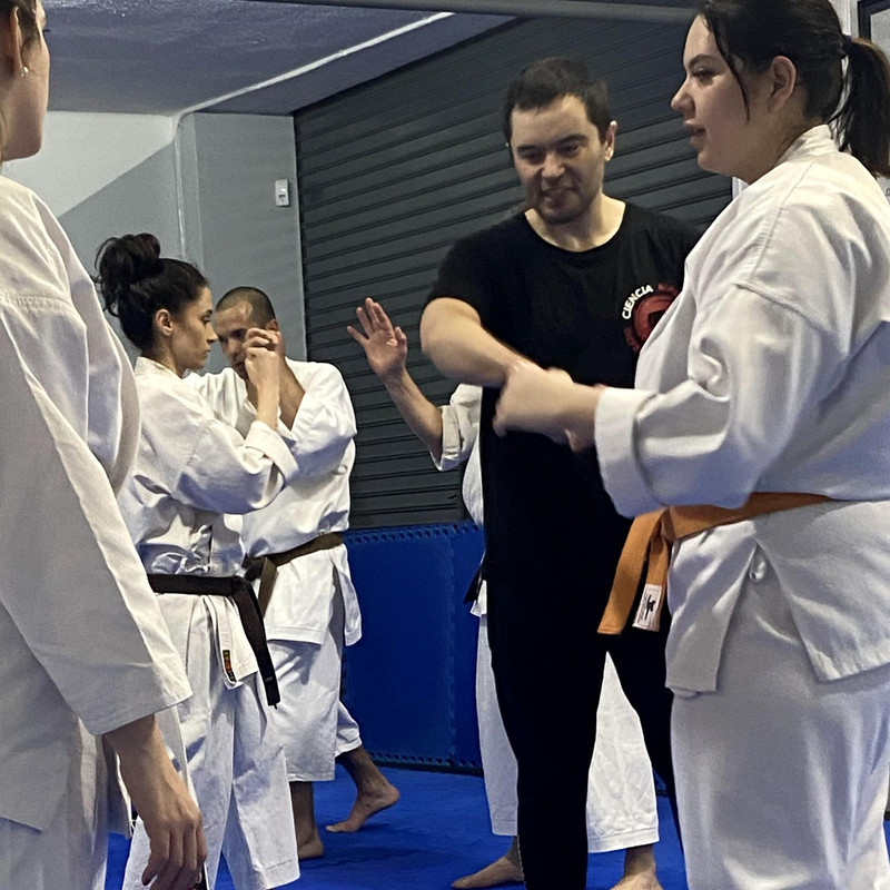 Manuel Gandini corrigiendo a una alumna durante un seminario en una escuela de karate