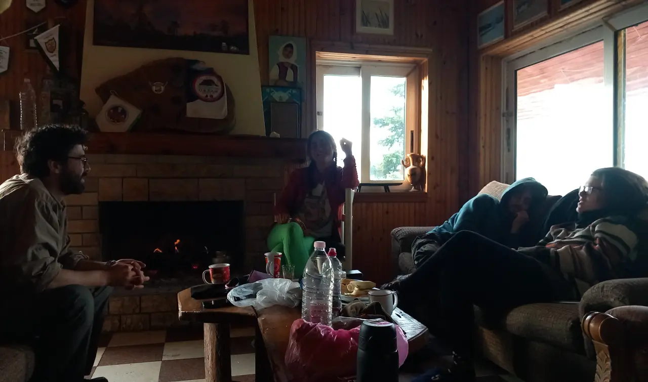 Fatih, Hilal and Efthimia talking next to a sleeping Nikos