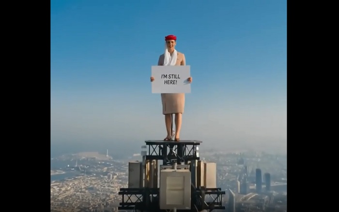 Aksi seorang wanita berseragam pramugari Emirates di puncak Burj Khalifa.