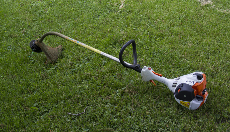 Gasoline Powered String Trimmer laying on the cut lawn