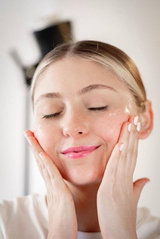 a woman using emollients on her skin to make her skin soft, smooth and supple. 