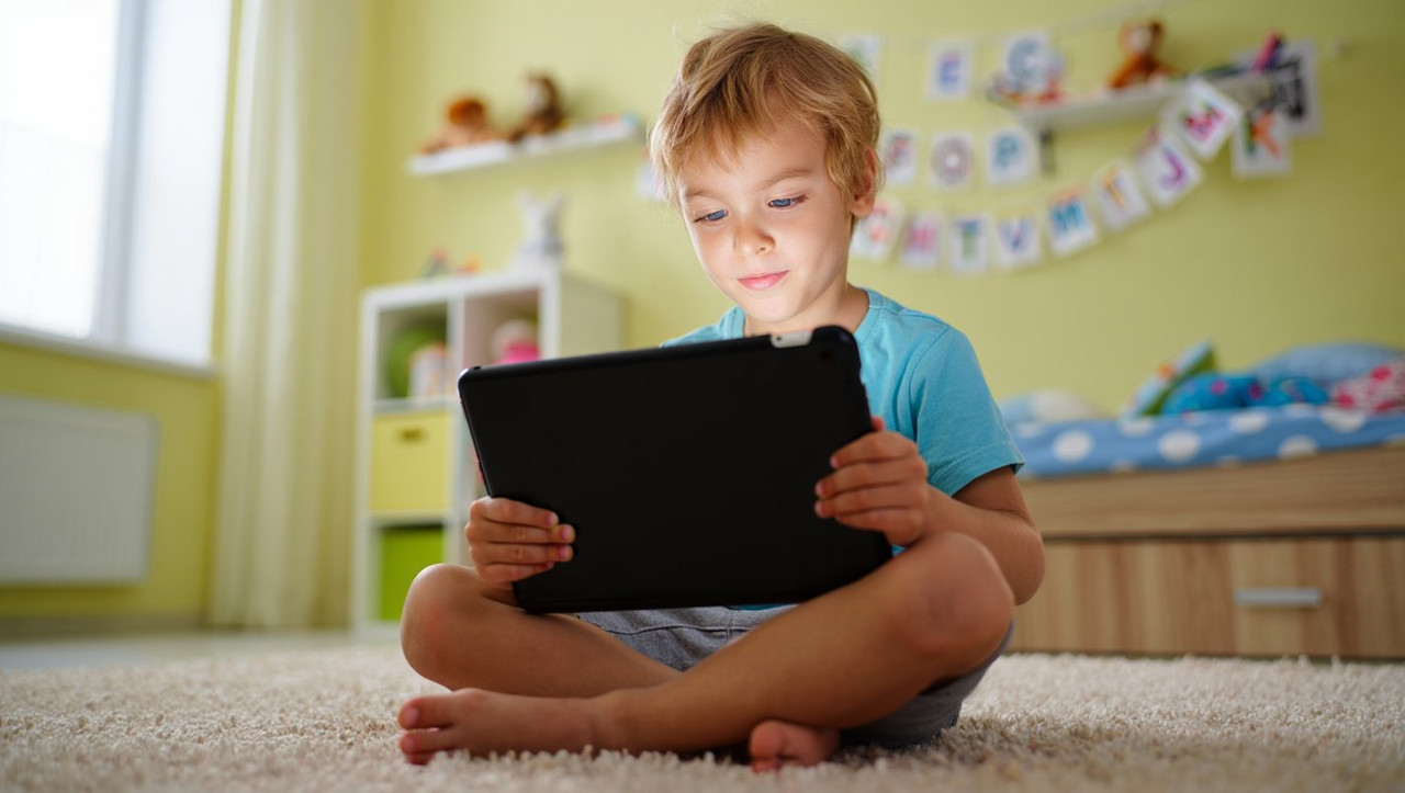 Ребенок с планшетом показывает детскую интернет зависимость