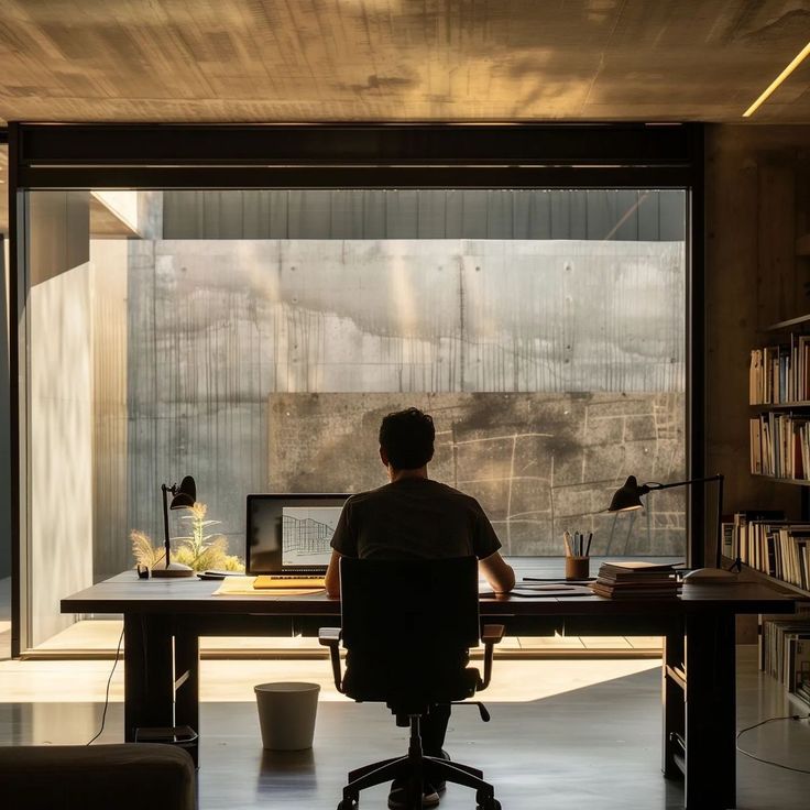 Na Baekjin's home office – architect at wooden desk with large windows, natural light, concrete walls and wooden bookshelf