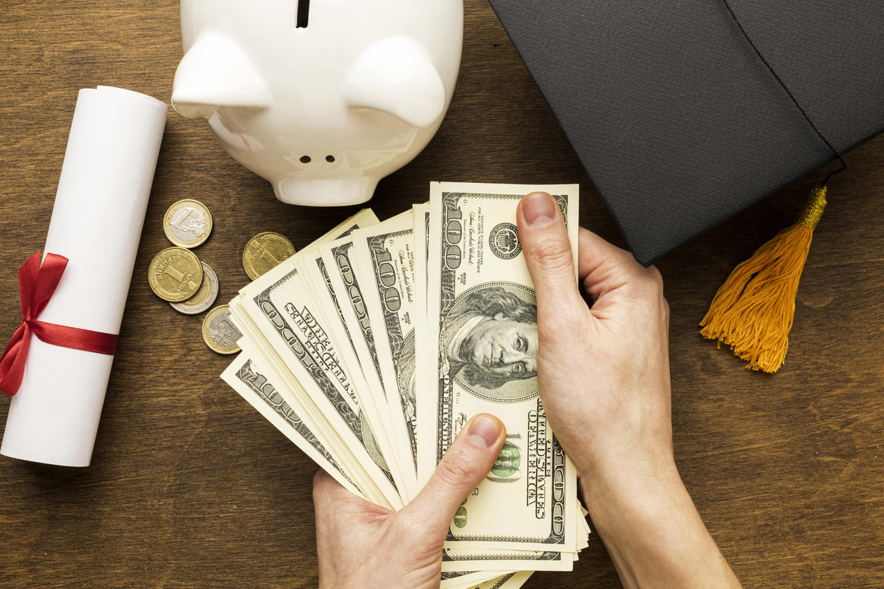 flat lay piggy bank with academic cap banknotes