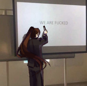 digital art of a woman in a suit with her back turned to the viewer and hair in a long s-shaped ponytail. She is pointing to a projection of the text "WE ARE FUCKED".
