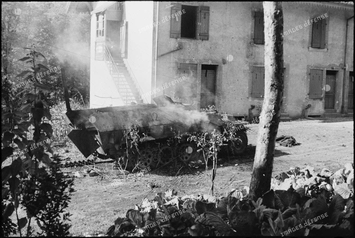 Une automitrailleuse semi-chenillée allemande Sd.Kfz 251 vient de sauter sur une mine dans le villag