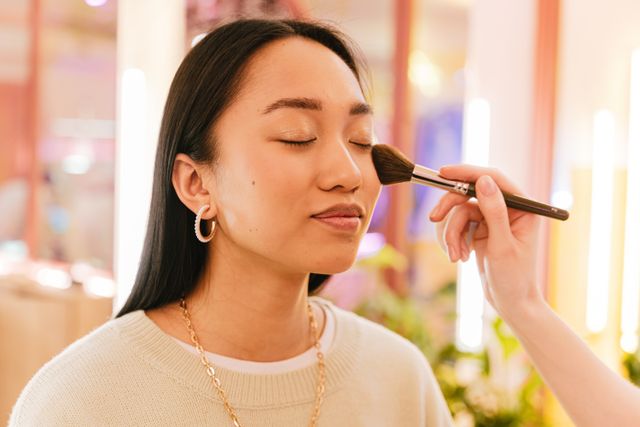 Close-up of a woman wearing natural-looking fall makeup with luminous skin, softly defined eyes, and muted rosy lips, alongside complexion product swatches. 