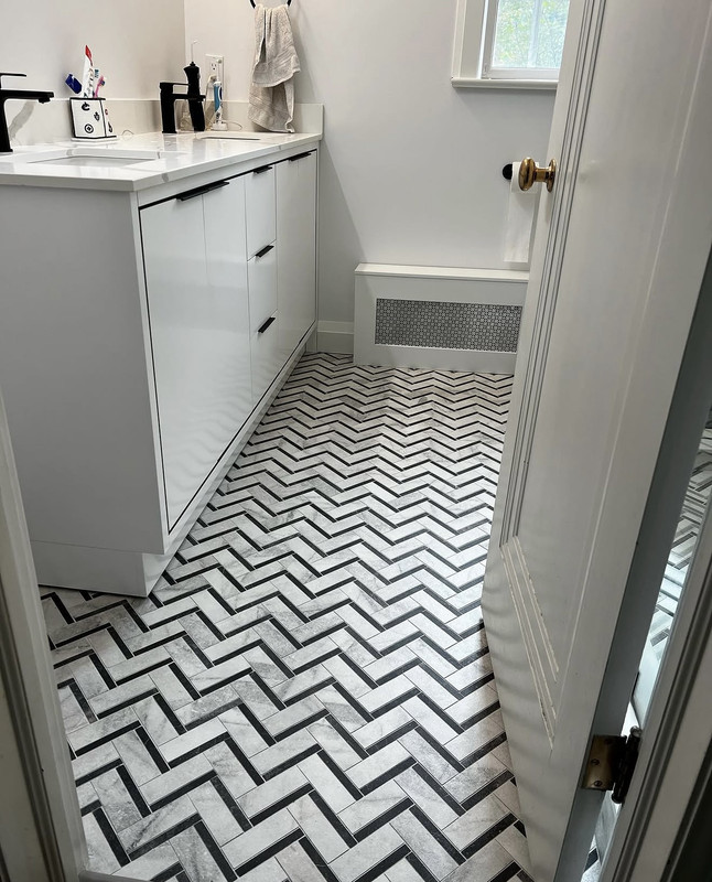 After — herringbone floor with charcoal liner tiles and white flat-front vanity