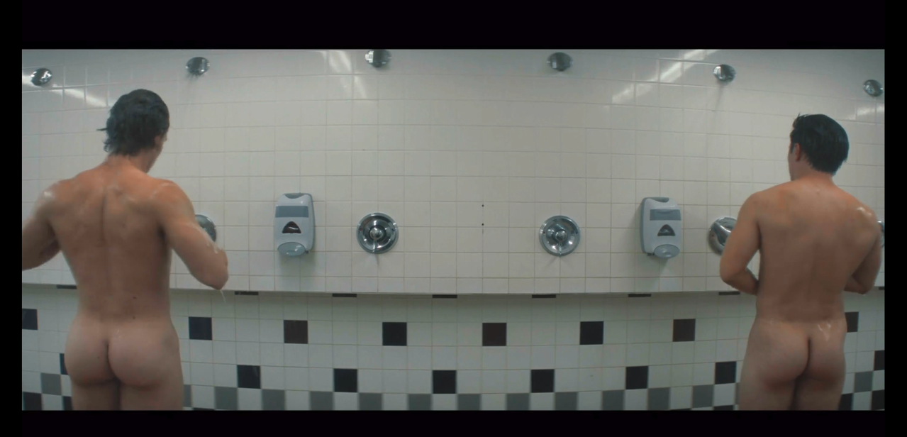 ilya and shane in the locker room showers. they're both naked, facing away from the camera, and on opposite sides of the frame.