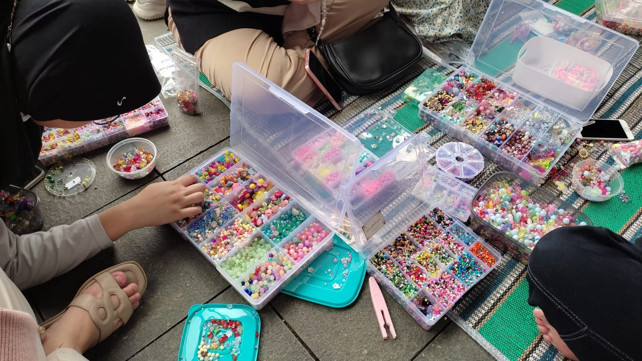 Para pengujung sedang mencoba workshop membuat manik-manik dalam gelaran Solo Art Market, Minggu (7/1/2023).