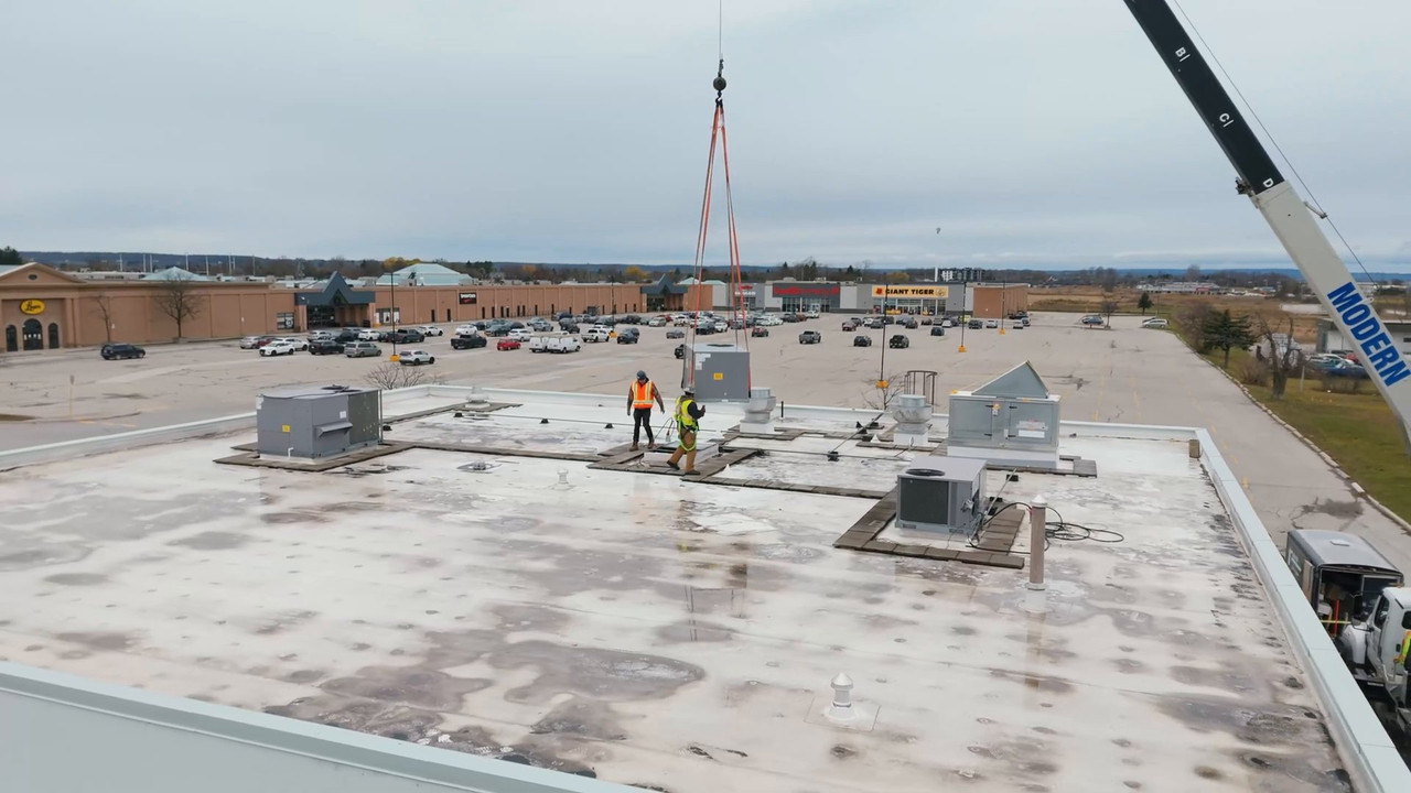Crane lifting a rooftop HVAC unit onto the Kelseys roof
