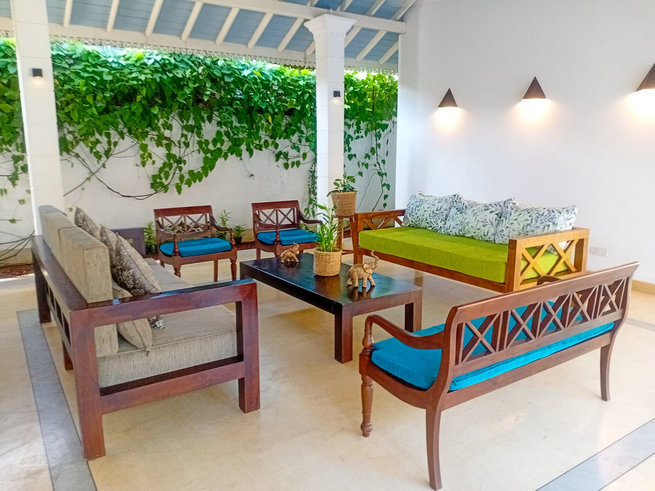 Open lounge with green cushions and vine-covered wall