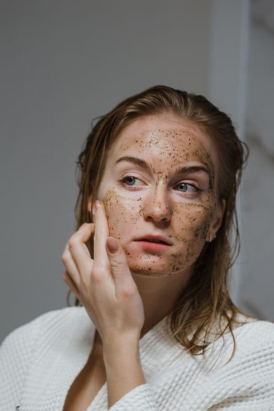 a woman scrubbing her face with physical exfoliating ingredeints to remove dead skin and get smooth and radiant skin 