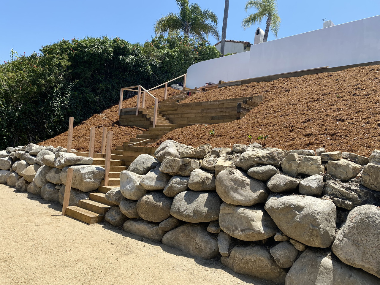 Hillside landscape with tiered planting, retaining walls, stone steps and lawn in Palos Verdes