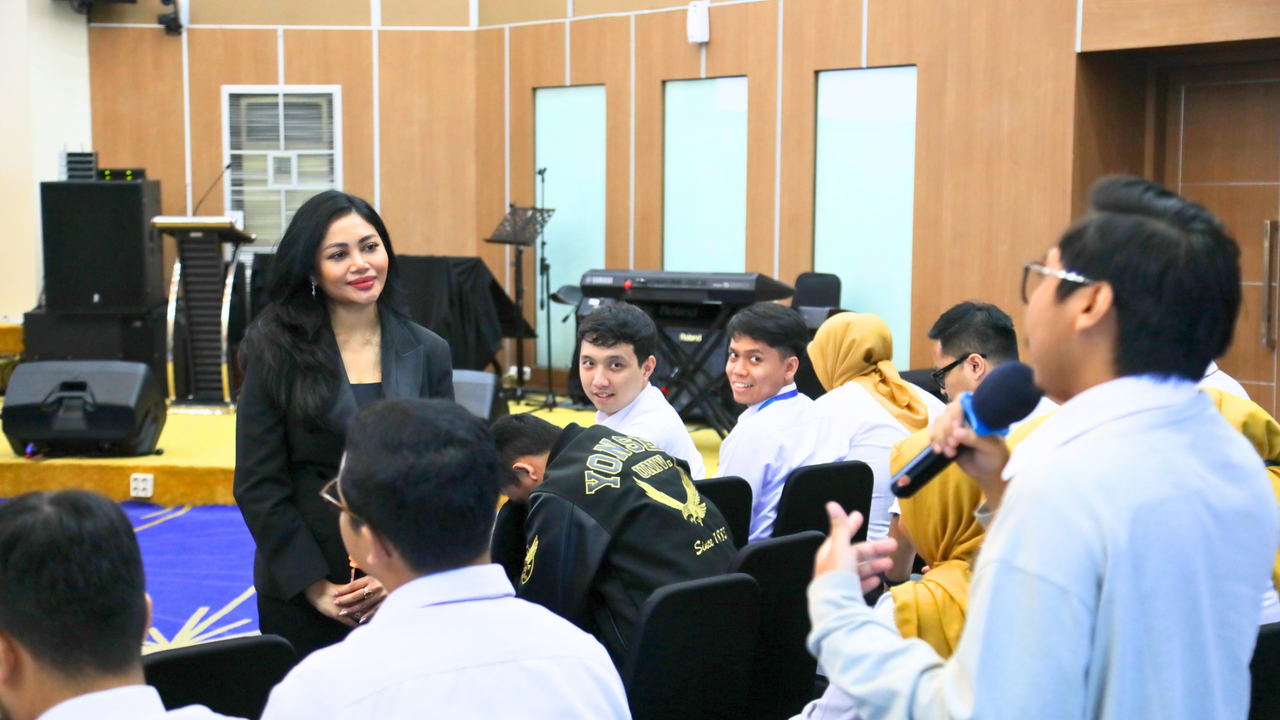 Presenter with microphone among seated students in a school hall