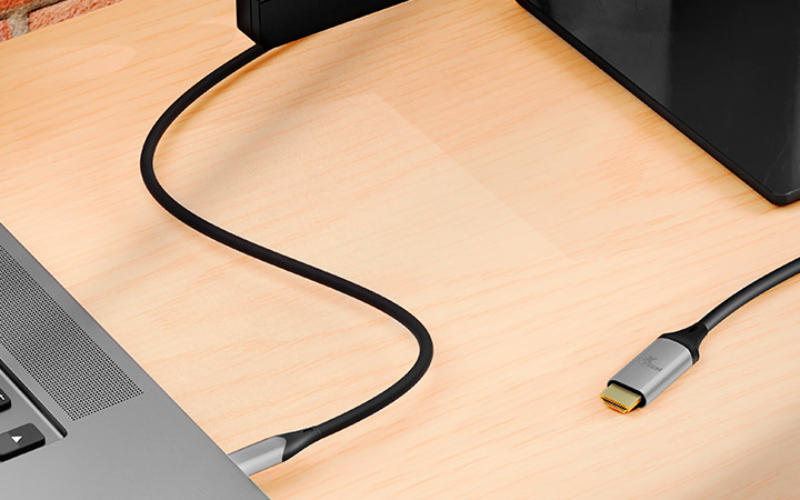 Cable USB-C a HDMI de Xtech conectado a un laptop y un televisor.