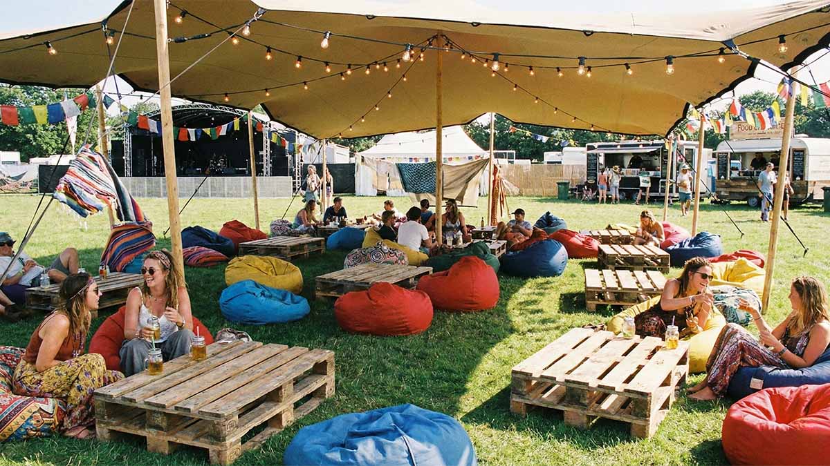 Уличная лаунж-зона с креслами-мешками под тентом, защищающим от солнца.