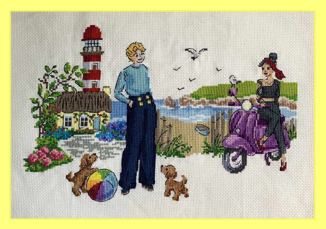 A cross stitch image of Stede and Ed at the lighthouse. Stede is wearing blue and standing with her hands in her pockets, smiling. Ed is half-seated on her purple motorcycle, giving Stede very alluring eyes. There is a seagull perched on the mirror. There are two small dogs running around, one playing with a colorful beach ball. In the background is the beach with a blue boat, the blue water, and the red and white lighthouse, rising up from a little yellow house surrounded by flowers.