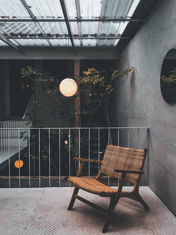 Industrial Balcony Design with Dark Metal Planters and Rattan Seating