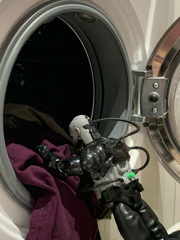 Black robot helping to Load in the dirty clothes into the washing machine. E374-E233-AF93-40-A1-88-E8-E51-CD94-B7-CCB