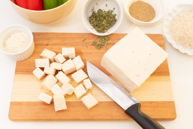 a chopboard with chopped paneer and paneer bar with a knife