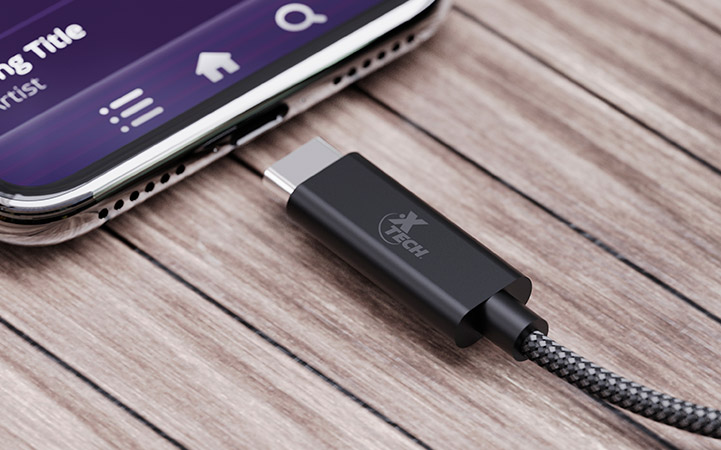 Adaptador Xtech USB-C a 3.5mm conectado a un smartphone.
