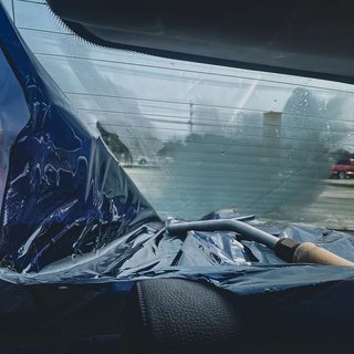 Technician removing old window tint film using a commercial steamer