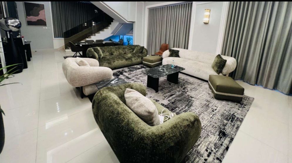 الصالة الثانية في فيلا فاخرة بعجمان، بتصميم حديث وإضاءة طبيعية تعزز أجواء الفخامة والدفء.